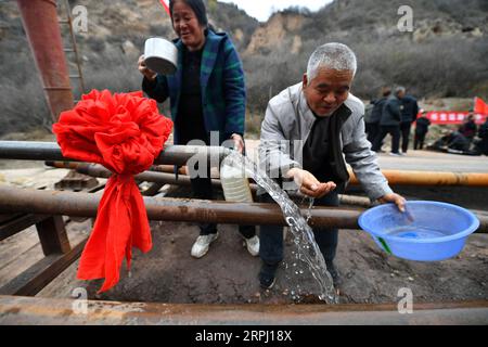 191122 -- COMTÉ DE YICHENG, 22 novembre 2019 -- Un villageois recueille de l'eau après qu'un puits en eau profonde ait commencé à pomper de l'eau souterraine dans le village de Nanling du comté de Yicheng, le 20 novembre 2019. Lorsque l'interrupteur a été tiré, l'eau a jailli de 403 mètres plus bas. Le tout premier puits en eau profonde de Nanling Village a été mis en service un matin tôt d hiver. Dans le passé, le village, qui s’étendait à travers les ravins des montagnes Zhongtiao dans le nord de la Chine, dépendait uniquement des fosses à boue pour stocker sa précieuse eau potable depuis des siècles. Hantées par la peur de la sécheresse, des générations avaient rêvé d’accès direct Banque D'Images