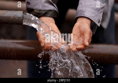 191122 -- COMTÉ DE YICHENG, 22 novembre 2019 -- Un villageois ramasse de l'eau avec les mains après qu'un puits en eau profonde ait commencé à pomper de l'eau souterraine dans le village de Nanling du comté de Yicheng, le 20 novembre 2019. Lorsque l'interrupteur a été tiré, l'eau a jailli de 403 mètres plus bas. Le tout premier puits en eau profonde de Nanling Village a été mis en service un matin tôt d hiver. Dans le passé, le village, qui s’étendait à travers les ravins des montagnes Zhongtiao dans le nord de la Chine, dépendait uniquement des fosses à boue pour stocker sa précieuse eau potable depuis des siècles. Hantées par la peur de la sécheresse, des générations avaient rêvé de dir Banque D'Images