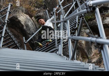 191205 -- CHENGDU, 5 décembre 2019 -- Mouse labo descend l'échelle en acier pour recevoir un touriste au village d'Atulie er, préfecture autonome de Liangshan Yi, province du Sichuan dans le sud-ouest de la Chine, 24 novembre 2019. Un garçon nommé Mouse labo a trouvé sa nouvelle vie dans le développement de sa ville natale, Atulie er Village. Le village d'Atulie er est un célèbre village à flanc de falaise dans la préfecture autonome de Liangshan Yi dans le Sichuan. Dans le passé, les villageois ici n'avaient pas accès aux routes. En sortant, ils devaient descendre une falaise de 800 mètres de haut par une échelle en rotin. En 2016, une échelle en acier à 2 556 marches a remplacé l'échelle Ratten, si Banque D'Images