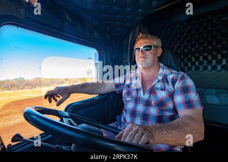 Transport lourd longue distance B-double chauffeur de camion au volant de son camion dans l'outback australien Banque D'Images