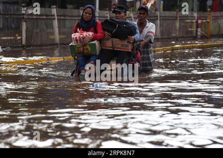 200102 -- JAKARTA, le 2 janvier 2020 -- des gens montent un pédicab traditionnel dans les eaux de crue à Jakarta, Indonésie, le 2 janvier 2020. À Jakarta, l'évacuation des personnes touchées par les inondations a continué, les eaux submergeant encore plusieurs parties de la ville, et six personnes ont été signalées mortes dans la ville, a déclaré M. Ridwan, porte-parole d'une agence de lutte contre les catastrophes à Jakarta. INDONÉSIE-JAKARTA-INONDATION AGUNGXKUNCAHYAXB. PUBLICATIONxNOTxINxCHN Banque D'Images
