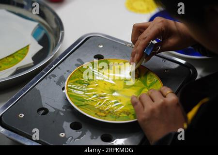 200114 -- JINGDEZHEN, 14 janvier 2020 -- Un ouvrier appose un autocollant sur des plaques en céramique mettant en vedette l'année chinoise du rat à Jingdezhen, dans la province de Jiangxi de l'est de la Chine, le 9 janvier 2020. Jingdezhen, également connue sous le nom de capitale de la porcelaine , est célèbre pour son savoir-faire en céramique élaboré qui nécessite un processus de production extrêmement compliqué. Dans le passé, de nombreux designers de porcelaine jeunes, compétents et ambitieux pouvaient créer de bons designs, mais avaient du mal à compléter indépendamment la production et les ventes. D'autre part, les entreprises traditionnelles qui pouvaient faire de la production et des ventes manquaient de nouvelle conception Banque D'Images