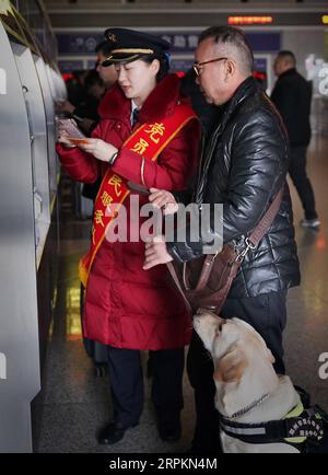 200114 -- ZHENGZHOU, le 14 janvier 2020 -- le chien-guide Xiaoqi attend pendant qu'un membre du personnel ferroviaire aide son maître à acheter des billets à la gare de Zhengzhoudong à Zhengzhou, province du Henan au centre de la Chine, le 14 janvier 2020. Le passager malvoyant surnommé Jin prendrait un train à grande vitesse avec son chien-guide Xiaoqi mardi à la gare de Zhengzhoudong. Il passa un appel téléphonique à la gare pour obtenir de l'aide. Le personnel de la gare a immédiatement élaboré un plan pour s'assurer que le passager et son chien-guide ont un voyage pratique et sûr sans barrières. CHINE-HENAN-ZHENGZHOU-G. Banque D'Images