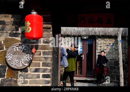 200115 -- RONGCHENG, le 15 janvier 2020 -- Yu Haiyang et sa mère travaillent dans leur cour dans le village de Yandunjiao à Rongcheng, dans la province du Shandong, dans l'est de la Chine, le 12 janvier 2020. Yandunjiao, un village côtier dans le Shandong, est plein de vitalité car de nombreux cygnes hivernent ici. À la fin de 2014, le service de train à grande vitesse entre Qingdao et Rongcheng a été lancé et de nombreux touristes sont venus ici pour voir des cygnes, déguster des spécialités locales et faire l'expérience d'un séjour chez l'habitant dans des maisons aux toits d'algues. Yu Haiyang, un villageois natif qui a travaillé à Singapour après l'obtention de son diplôme, est retourné dans sa ville natale et a commencé un bus chez l'habitant Banque D'Images