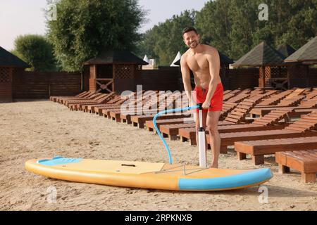Homme pompant la planche de SUP sur la rive de la rivière Banque D'Images