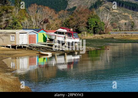 Un grand bateau sur la rampe d'un hangar à bateaux beaucoup plus petit. Marlborough Sounds, île du sud, Aotearoa / Nouvelle-Zélande Banque D'Images