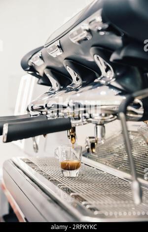 Espresso coulant du porte-filtre de la machine à café dans la tasse en verre Banque D'Images