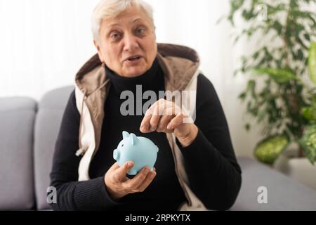 Gros plan d'une femme âgée tenant une caisse d'argent de porc. Femme âgée mains tenant une porcgybank. Concept d'économie d'argent pour les personnes âgées. Banque D'Images