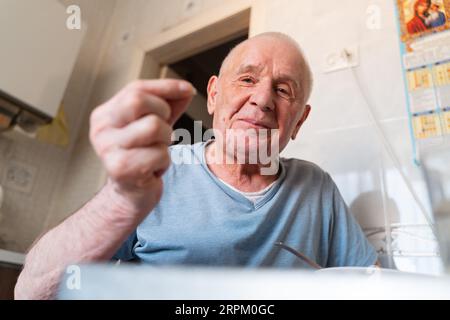 Homme âgé de 80 ans à la maison prenant des pilules à la maison, portrait en gros plan. Retraite heureuse et saine avec soins médicaux Banque D'Images