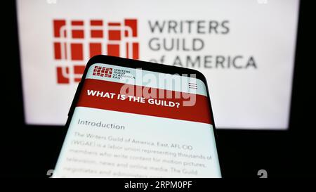 Téléphone portable avec le site Web du syndicat Writers Guild of America East (WGAE) à l'écran devant le logo. Effectuez le focus sur le coin supérieur gauche de l'écran du téléphone. Banque D'Images