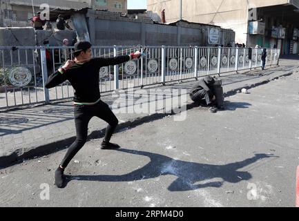 200128 -- BAGDAD, le 28 janvier 2020 -- Un manifestant lance des pierres lors d'affrontements avec les forces de sécurité irakiennes à Bagdad, capitale de l'Irak, le 28 janvier 2020. Des dizaines de manifestants antigouvernementaux ont poursuivi leurs manifestations mardi, réclamant une réforme globale, la lutte contre la corruption, de meilleurs services publics et plus de possibilités d'emploi. Khalil Dawood IRAK-BAGDAD-PROTEST BaixPing PUBLICATIONxNOTxINxCHN Banque D'Images