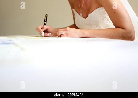 Mariée caucasienne signant le document de mariage légal après la cérémonie. Banque D'Images