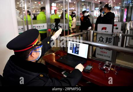 200211 -- XI AN, 11 février 2020 -- Un membre du personnel de Xi an North Railway Station mesure la température des passagers à une sortie de Xi an North Railway Station à Xi an, province du Shaanxi au nord-ouest de la Chine, 10 février 2020. Avec l'augmentation du flux de passagers dans divers centres de transport, Xi an a lancé un système de gestion de réseau pour les personnes qui viennent à Xi an. Toutes les personnes entrant à Xi an par l'aéroport international de Xianyang, la gare ferroviaire de Xi an, la gare ferroviaire du nord de Xi an, la gare ferroviaire du sud de Xi an, la gare ferroviaire de Huyi et la gare ferroviaire du palais d'Epang doivent être classifiées et filtrées un b. Banque D'Images