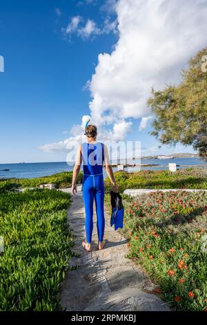 Jeune homme avec lunettes de plongée, tuba, palmes bleues et combinaison bleue, Paros, Cyclades, Grèce Banque D'Images