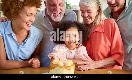 Famille multi-génération célébrant l'anniversaire de la petite-fille à la maison avec gâteau Banque D'Images