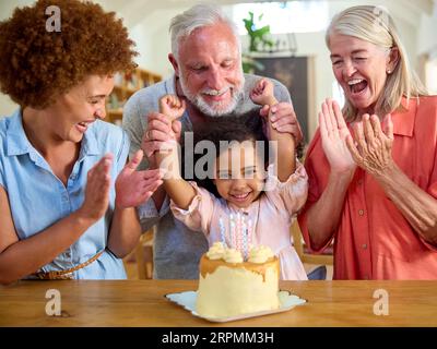 Famille multi-génération célébrant l'anniversaire de la petite-fille à la maison avec gâteau Banque D'Images