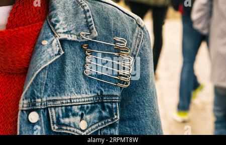 femme avec veste en denim et épingles de sécurité énormes, déclaration de mode, les gens occupés marchant sur le trottoir Banque D'Images