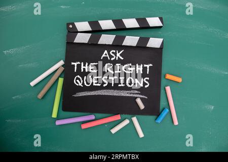 Posez les bonnes questions. clapper de film noir avec des morceaux de craie sur un fond de tableau vert. Banque D'Images