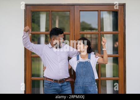 Heureux couple de la famille indienne montrant la nouvelle clé de la maison à la caméra alors qu'en face de la porte. Succès dans le déménagement Banque D'Images