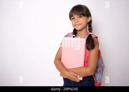 Souriant actif excellente meilleure écolière étudiante tenant des livres et des cahiers allant à l'école portant le sac isolé dans le fond blanc Banque D'Images