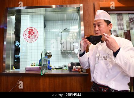 200222 -- TIANJIN, le 22 février 2020 -- Yang Ming fait une pause à l'extérieur de la cuisine de son restaurant à Tianjin, dans le nord de la Chine, le 22 février 2020. Chaque jour, Yang Ming, le propriétaire de 55 ans du restaurant Caigentan, fournit plus de 20 plats à emporter gratuits aux membres du personnel luttant contre la nouvelle épidémie de coronavirus dans les communautés voisines. Cette idée est d'abord venue à l'esprit de Yang lorsqu'il a entendu les travailleurs communautaires avoir des problèmes avec les repas car la plupart des restaurants avaient été fermés. Yang travaille de 7 h à 7 h tous les jours pour préparer et livrer les plats à emporter pour le déjeuner et le dîner à temps. C'est sûrement mak Banque D'Images