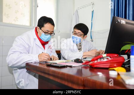 200223 -- XIAOGAN, 23 février 2020 -- Liu Jinglun L diagnostique l'état des patients avec le médecin Liu Shuming à l'hôpital des premiers peuples de Xiaogan dans la ville de Xiaogan, dans la province du Hubei en Chine centrale, le 19 février 2020. Liu Jinglun, 42 ans, médecin du premier hôpital affilié de l'Université de médecine de Chongqing, est arrivé à Xiaogan en tant que membre du premier groupe d'équipes médicales de Chongqing pour aider à lutter contre la nouvelle épidémie de COVID-19 à coronavirus dans le Hubei. En tant que chef d'équipe pour les cas graves, Liu déploie tous les efforts possibles, y compris la tenue de consultations de groupe de médecins, l'inspection des services Banque D'Images