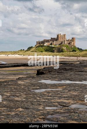 Vue au sud du château de Bamburgh, un célèbre monument du Northumberland et une attraction touristique vue depuis la plage à marée basse en août 2023. Banque D'Images