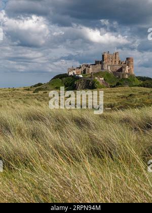 Vue au sud du château de Bamburgh, un célèbre monument du Northumberland et une attraction touristique vue depuis les dunes à marée basse en août 2023. Banque D'Images