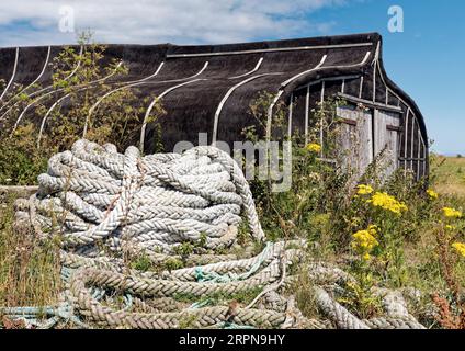 Les célèbres hangars de pêcheur de Lindisfarne fabriqués à partir des restes de vieux bateaux sont l'une des nombreuses attractions de ce lieu historique. Banque D'Images