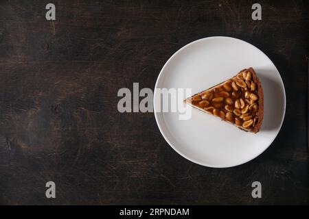 Cheesecake au caramel et aux arachides maison sur fond sombre. Délicieux gâteau de boulangerie le matin. Banque D'Images