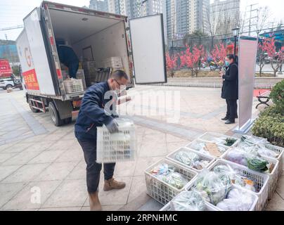 200229 -- SANMENXIA, 29 février 2020 -- les membres du personnel d'une plateforme de commerce électronique envoient des légumes à la porte d'une communauté, à Sanmenxia, dans la province du Henan, au centre de la Chine, le 28 février 2020. Récemment, Sanmenxia a réalisé un projet visant à assurer l’approvisionnement en légumes des résidents grâce à un système de distribution communautaire développé par une plateforme de commerce électronique. La plate-forme transporte les légumes des bases de plantation des agriculteurs locaux vers les communautés résidentielles. Les résidents locaux récupèrent leurs commandes séparément. De cette façon, les résidents peuvent acheter des légumes frais sans contact dans l'ensemble du processus. Jusqu'à présent, Th Banque D'Images