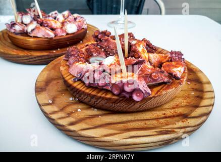 Les plaques en bois délicieux de style galicien poulpe cuit avec le paprika et l'huile d'olive. Pulpo a la gallega Banque D'Images