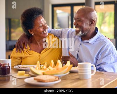 Couple senior à la maison profitant du petit déjeuner autour de la table ensemble Banque D'Images