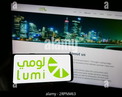 Personne tenant le smartphone avec le logo de la société saoudienne de location de voitures Lumi sur l'écran en face du site Web. Concentrez-vous sur l'affichage du téléphone. Banque D'Images