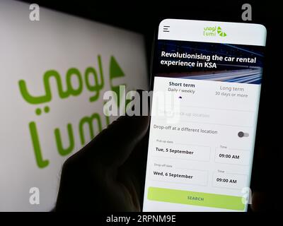 Personne tenant un téléphone portable avec la page Web de la société saoudienne de location de voitures Lumi sur l'écran devant le logo. Concentrez-vous sur le centre de l'écran du téléphone. Banque D'Images