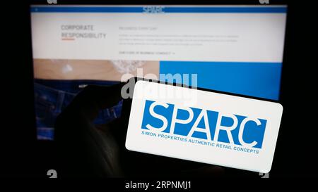 Personne détenant un téléphone portable avec le logo de la société de détail américaine SPARC Group LLC sur l'écran devant la page Web de l'entreprise. Concentrez-vous sur l'affichage du téléphone. Banque D'Images