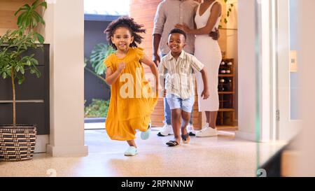 Famille rentrant à la maison ouvrant la porte d'entrée et enfants rentrant Banque D'Images