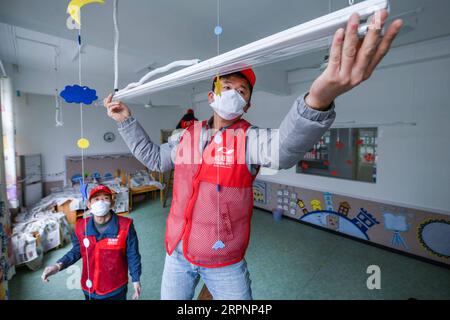 200303 -- CIXI, 3 mars 2020 -- des volontaires ajustent une lumière de désinfection ultraviolette dans un jardin d'enfants à Cixi, dans la province du Zhejiang de l'est de la Chine, le 3 mars 2020. Des bénévoles sont venus dans les jardins d’enfants, les écoles primaires et les écoles secondaires pour aider la faculté à installer du matériel de désinfection, désinfecter les salles de classe et coller des affiches sur les connaissances en matière de prévention et de contrôle de l’épidémie. CHINE-ZHEJIANG-DÉSINFECTION-VOLONTAIRE CN XuxYu PUBLICATIONxNOTxINxCHN Banque D'Images