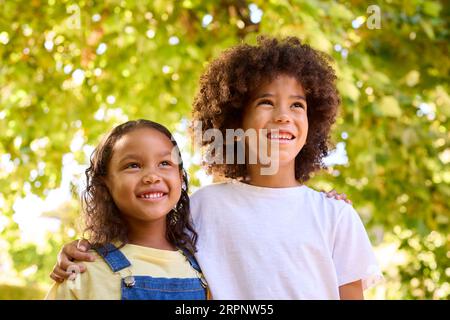 Portrait de garçon et fille debout dans le jardin souriant à la caméra Banque D'Images