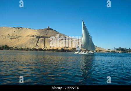 Felouque naviguant devant le Qubbet el-Hawan sur les rives du Nil Assouan Egypte Banque D'Images