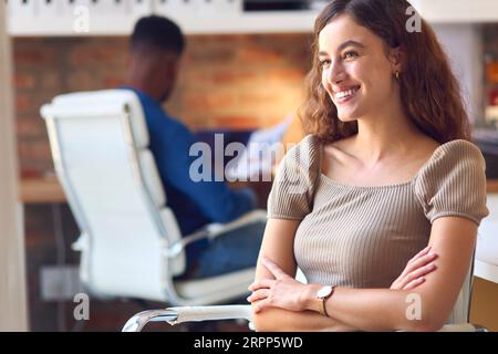 Portrait de Jeune femme d'affaires souriante assise au bureau dans le bureau moderne Banque D'Images