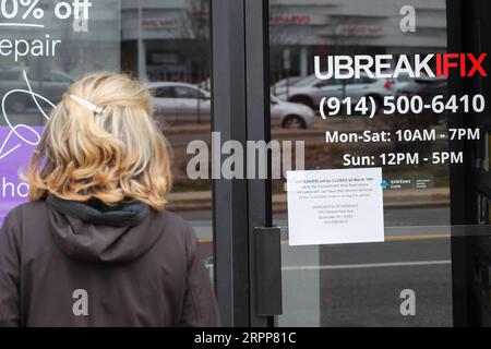 200312 -- NEW YORK, le 12 mars 2020 -- Une femme lit un avis de fermeture temporaire sur la porte d'un magasin situé dans la zone de confinement d'un kilomètre à New Rochelle, dans l'État de New York, aux États-Unis, le 12 mars 2020. L’État américain de New York a mis en place une soi-disant zone de confinement dans un hotspot COVID-19 jeudi, avec des troupes de la Garde nationale envoyées sur place pour nettoyer les surfaces et livrer de la nourriture aux personnes en quarantaine. ÉTATS-UNIS-NEW YORK-NEW ROCHELLE- ZONE DE CONFINEMENT -COVID-19 WANGXYING PUBLICATIONXNOTXINXCHN Banque D'Images