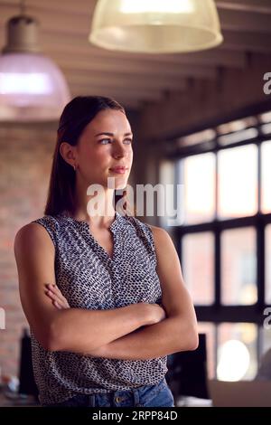 Portrait de jeune femme d'affaires avec l'expression sérieuse debout dans le bureau occupé Banque D'Images