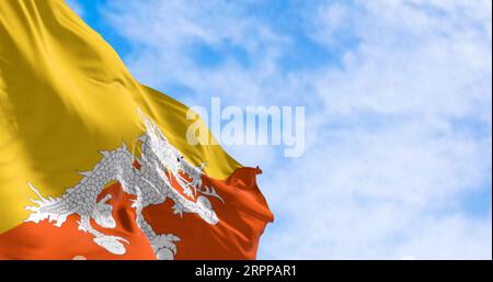 Drapeau national du Bhoutan agitant dans le vent par temps clair. Triangle supérieur jaune et triangle inférieur orange, avec un dragon blanc tenant des bijoux Banque D'Images