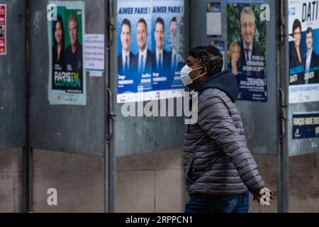 200315 --PARIS, le 15 mars 2020 -- Un homme passe devant des affiches de candidats à Paris, France, le 15 mars 2020. Les bureaux de vote sont ouverts dans toute la France dimanche pour le premier tour des élections municipales après que des mesures supplémentaires ont été récemment imposées pour freiner la propagation du coronavirus. Les stations devraient suivre les directives sanitaires recommandées par le gouvernement et les experts de la santé, ont rapporté les médias français, y compris le nettoyage régulier des poignées de porte, des tables et des cabines de vote. D'autres mesures comprennent l'évitement des files d'attente, l'application d'une distance de sécurité entre les électeurs et la garantie de la priorité pour l'el Banque D'Images