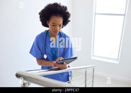 Médecin ou infirmière avec tablette numérique vérifiant les notes du patient sur les escaliers dans l'hôpital Banque D'Images