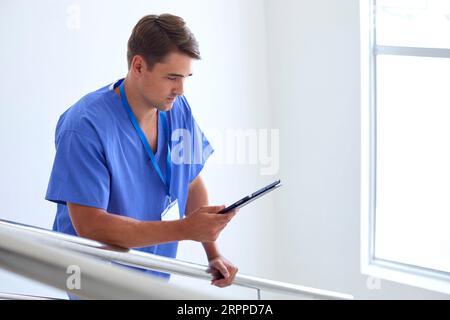 Médecin ou infirmière avec tablette numérique vérifiant les notes du patient sur les escaliers dans l'hôpital Banque D'Images