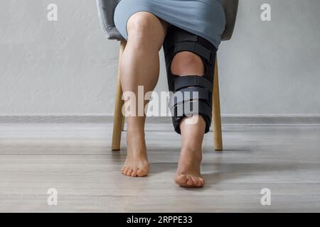 Femme portant une attelle de jambe avec des panneaux latéraux réglables pour immobiliser et soutenir son genou après la chirurgie Banque D'Images