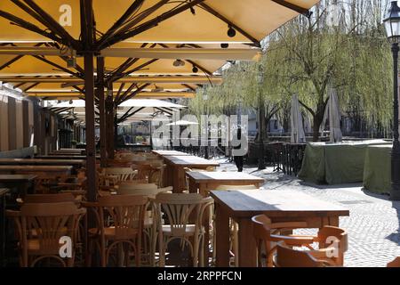 200317 -- LJUBLJANA, le 17 mars 2020 -- Un piéton passe devant des chaises vides d'un restaurant à Ljubljana, capitale de la Slovénie, le 16 mars 2020. Le nombre de cas confirmés de COVID-19 en Slovénie est passé à 253, selon le gouvernement lundi. Le gouvernement a décidé de suspendre les transports publics à partir de dimanche minuit et de prolonger indéfiniment le décret précédent sur la fermeture de tous les établissements d'enseignement. SLOVÉNIE-LJUBLJANA-COVID-19 PengxLijun PUBLICATIONxNOTxINxCHN Banque D'Images