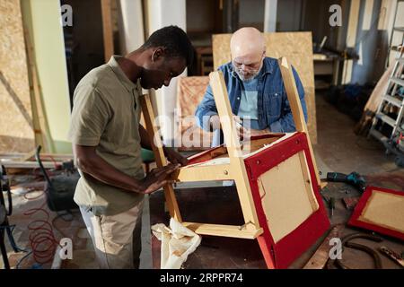 Portrait de deux personnes réparant des meubles anciens tout en travaillant dans l'atelier de menuiserie ensemble, espace de copie Banque D'Images